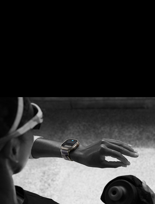 Una corredora mira el Apple Watch Ultra 2 que lleva en la muñeca izquierda mientras hace el gesto de doble toque con los dedos índice y pulgar de la mano izquierda.